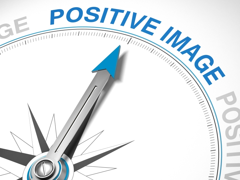 close-up of compass pointing towards the text "positive image"