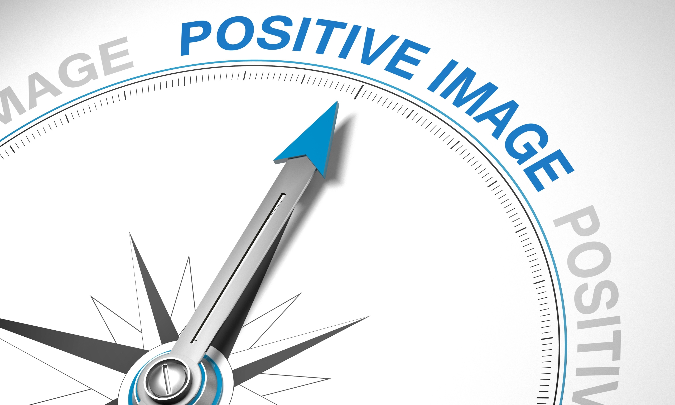 close-up of compass pointing towards the text "positive image"