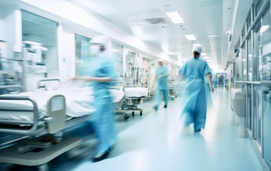 Long exposure blurred motion of medical doctors and nurses in a hospital ward wearing blue aprons, walking down a corridor