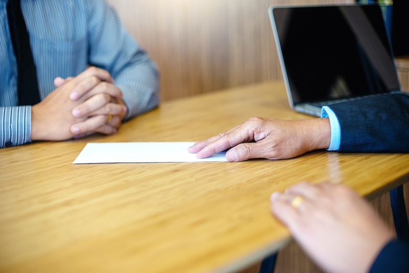 A person handing an envelope to another person
