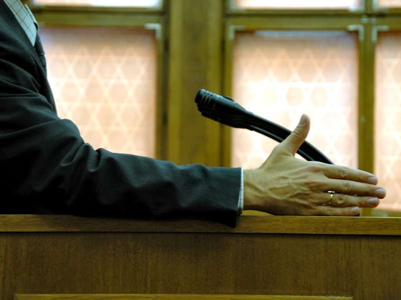 Man on a stand in the courtroom with his hand out