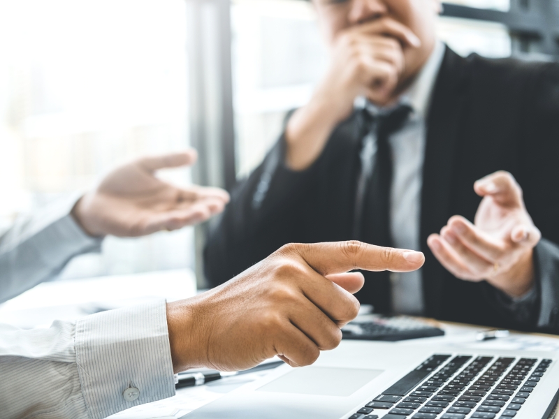 Image of two businessmen having a conversation pointing into a laptop screen