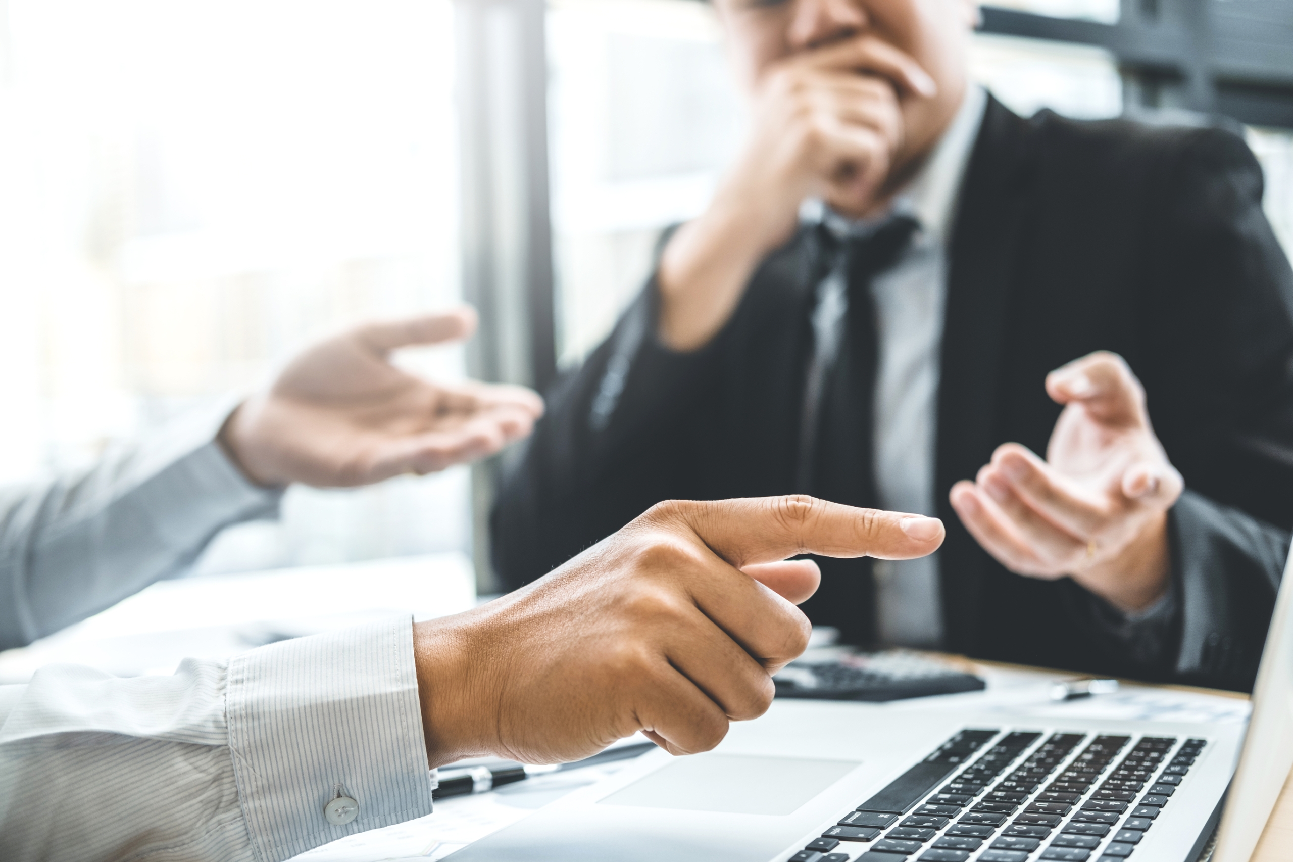 Image of two businessmen having a conversation pointing into a laptop screen