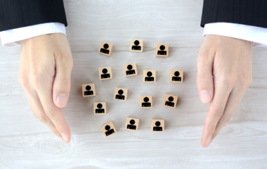 A person's hands with small cubes with people icons on