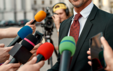 Person in suit surrounded by microphones