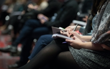 people sat down taking notes on paper and pen
